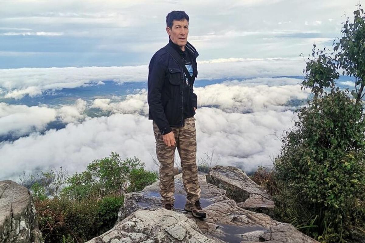 a man standing on top of a rock in the clouds