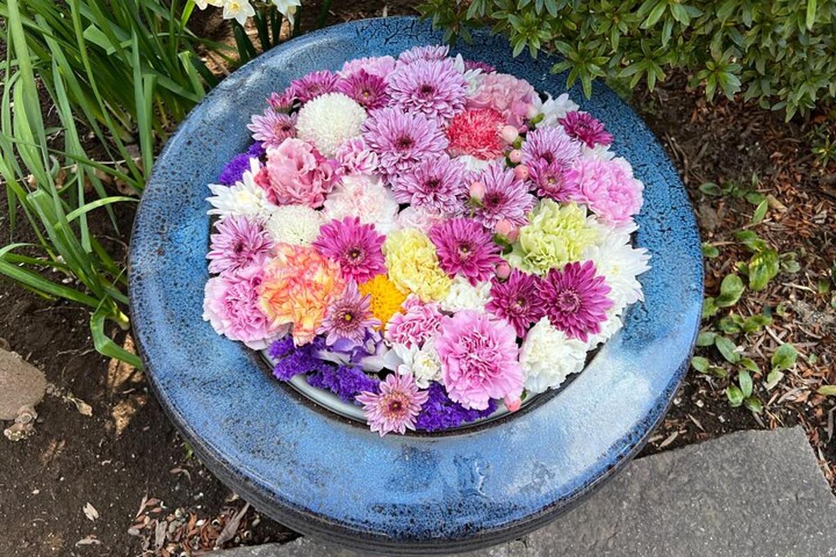 Un recipiente azul lleno de flores de colores en el suelo.