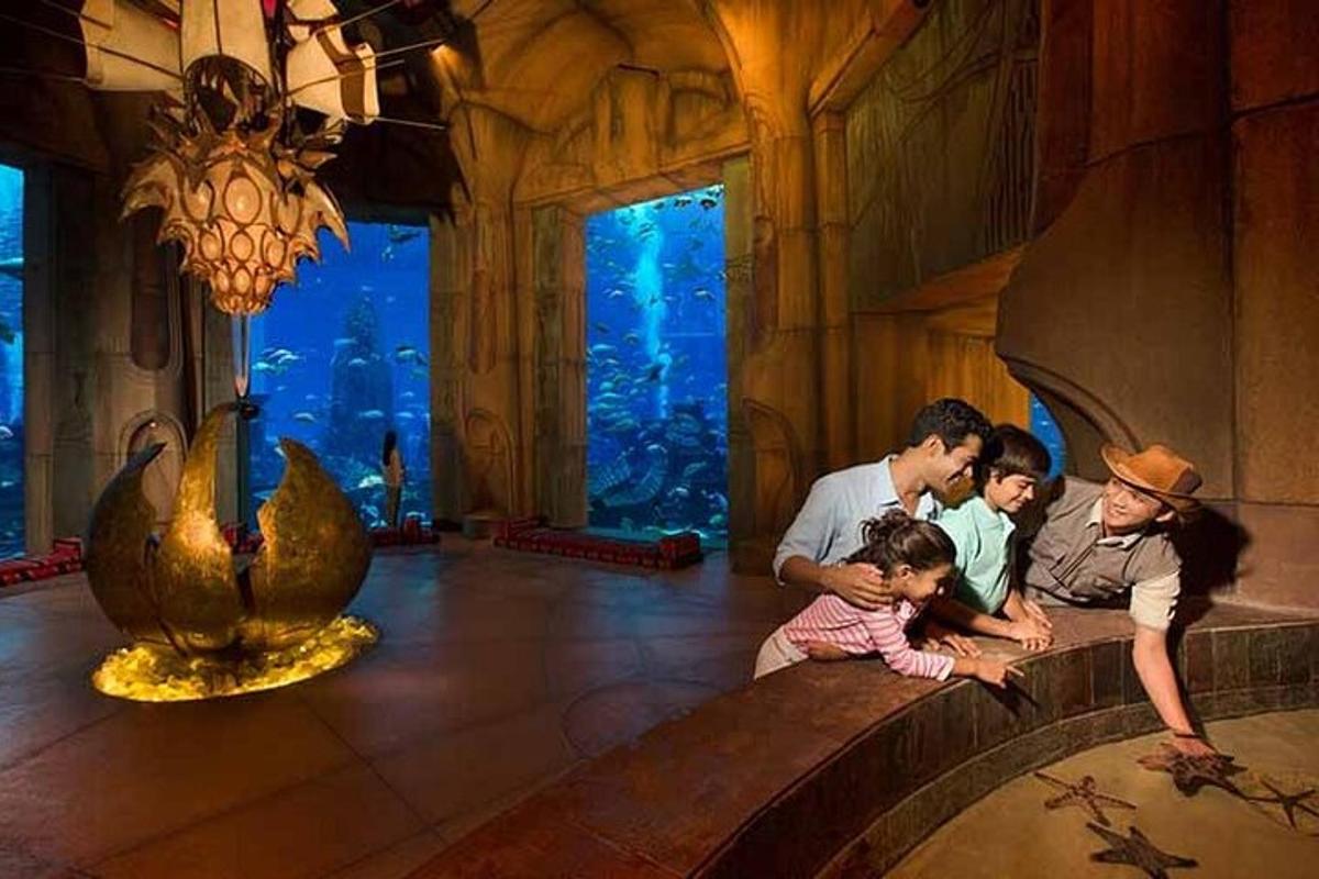 a family sitting on a wall in an aquarium
