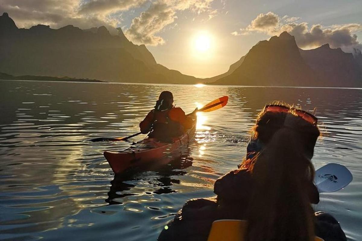 two people kayaking on the water at sunset