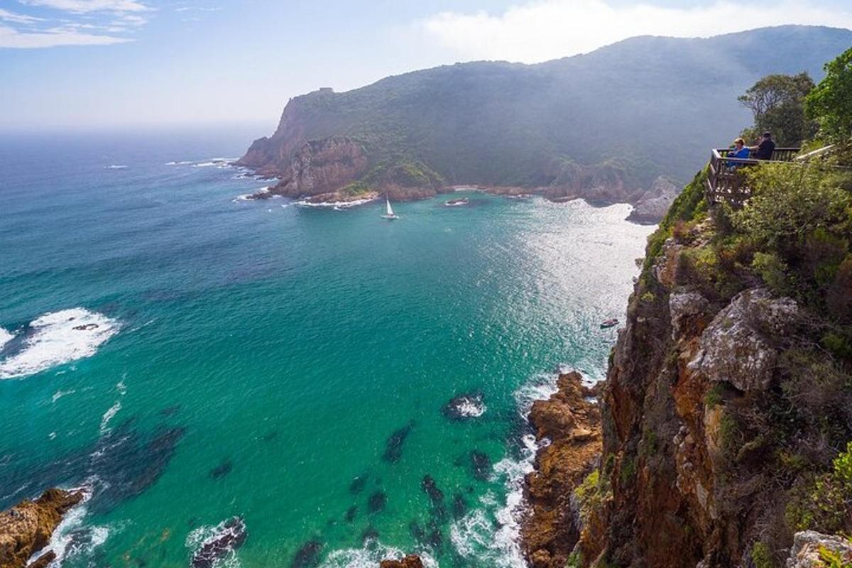skupina ljudi, ki stojijo na pečini s pogledom na ocean