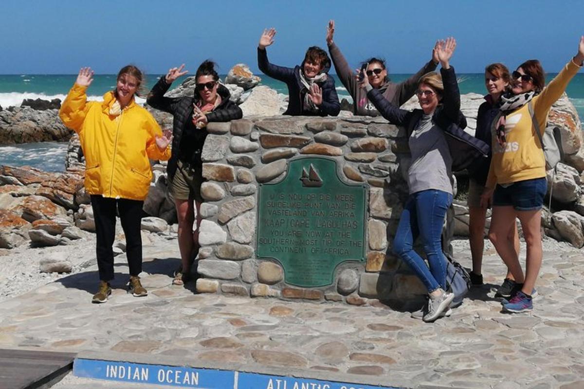 un gruppo di persone in piedi accanto a un cartello sulla spiaggia