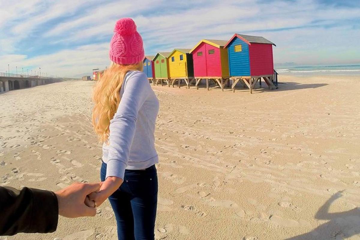 una donna in piedi sulla spiaggia vicino a una fila di cabine