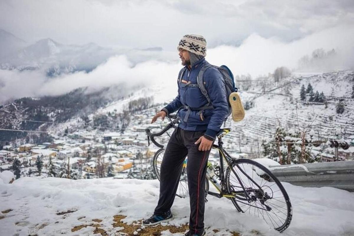 a man standing next to a bike in the snow