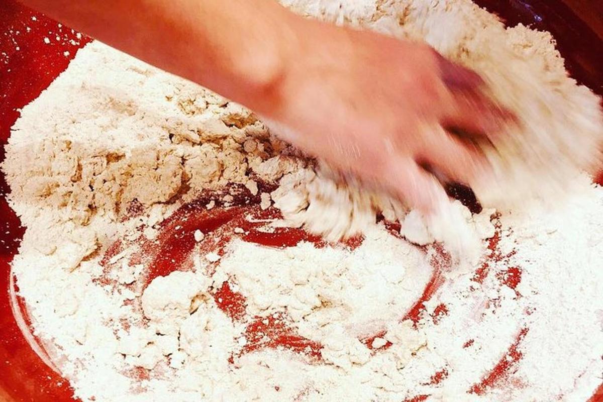 a persons hand is stirring a bowl of flour