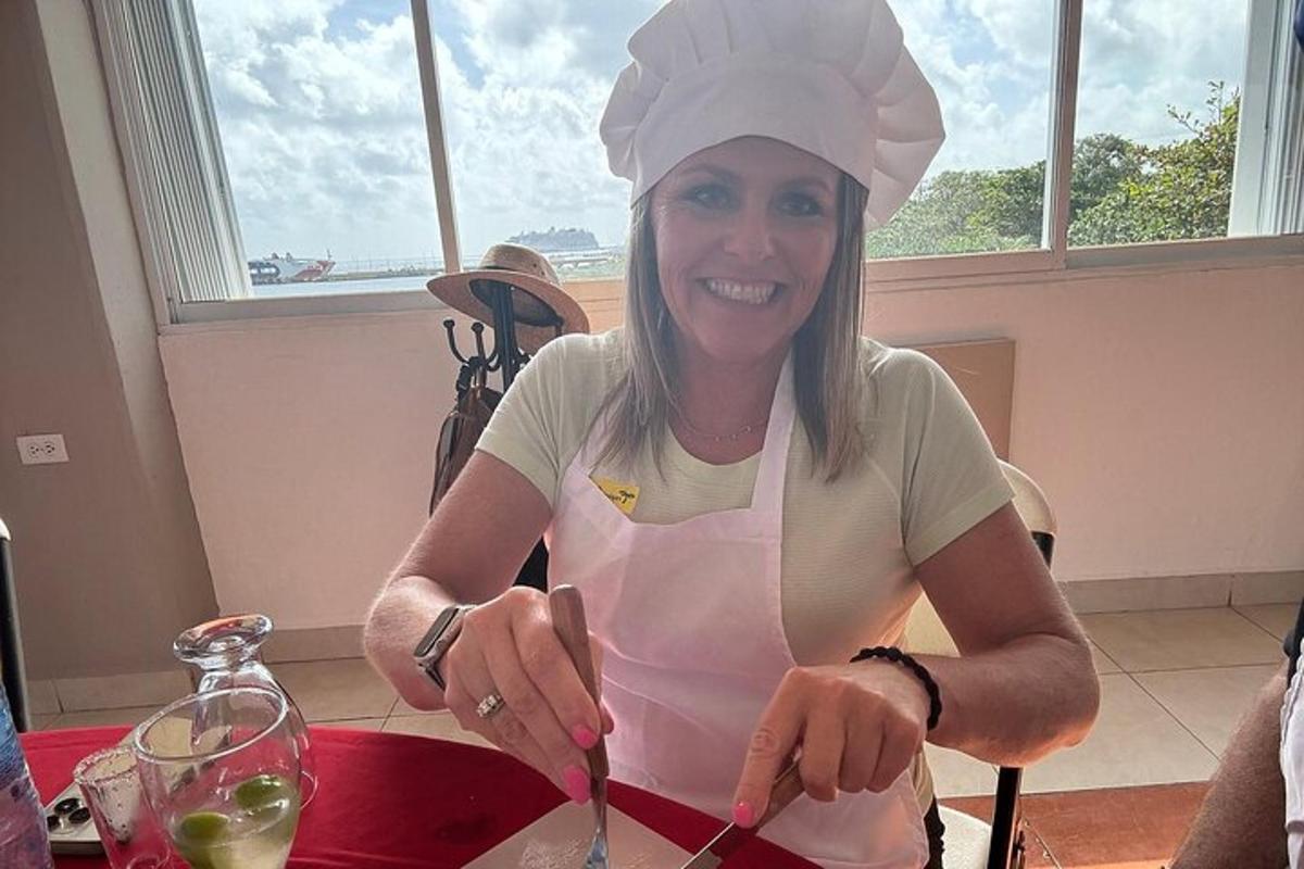 uma mulher sentada à mesa com um chapéu de chef cortando comida