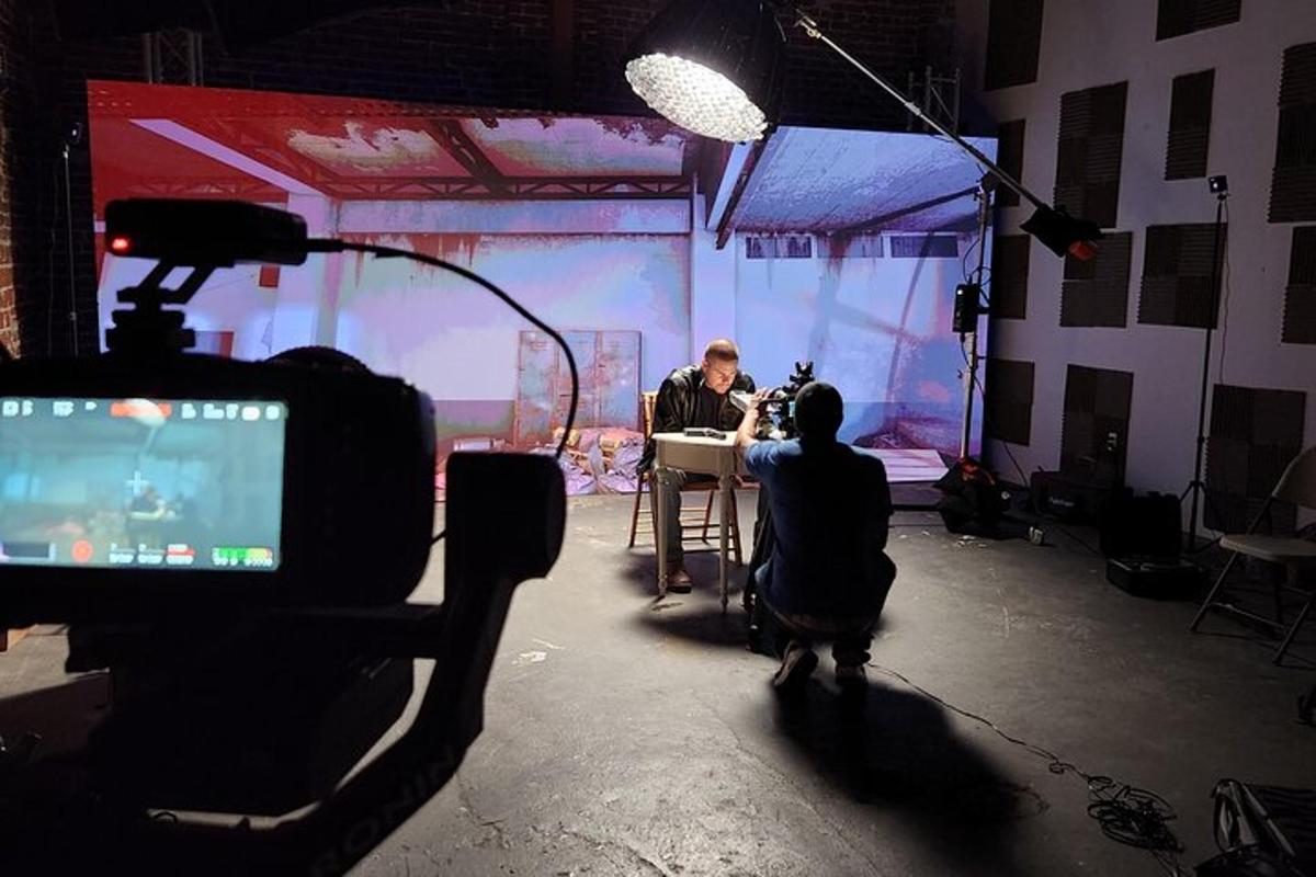 muž sedící u stolu před videokamerou