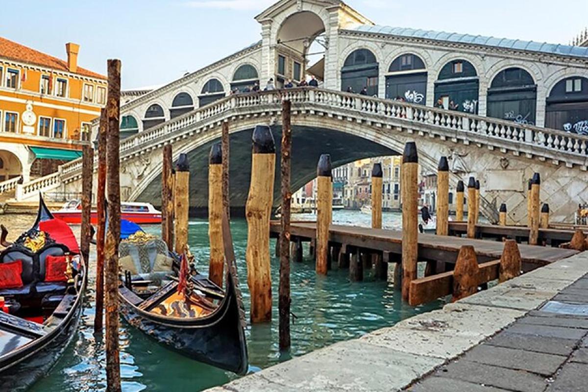 a bridge and two gondolas in the water near a pier