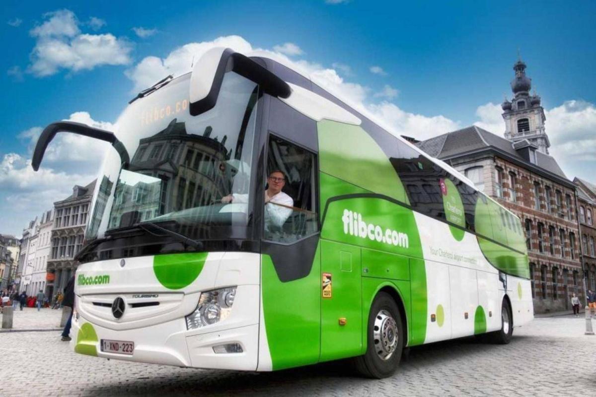 a green and white bus parked in front of a building
