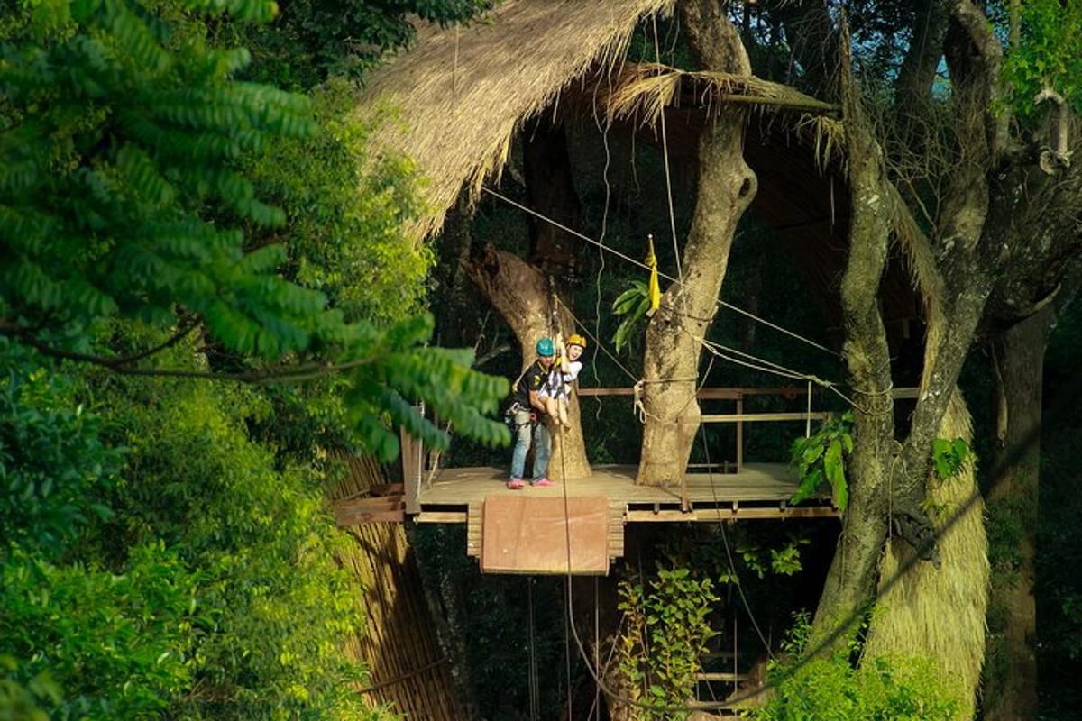 dua orang berdiri di atas jambatan gantung antara pokok