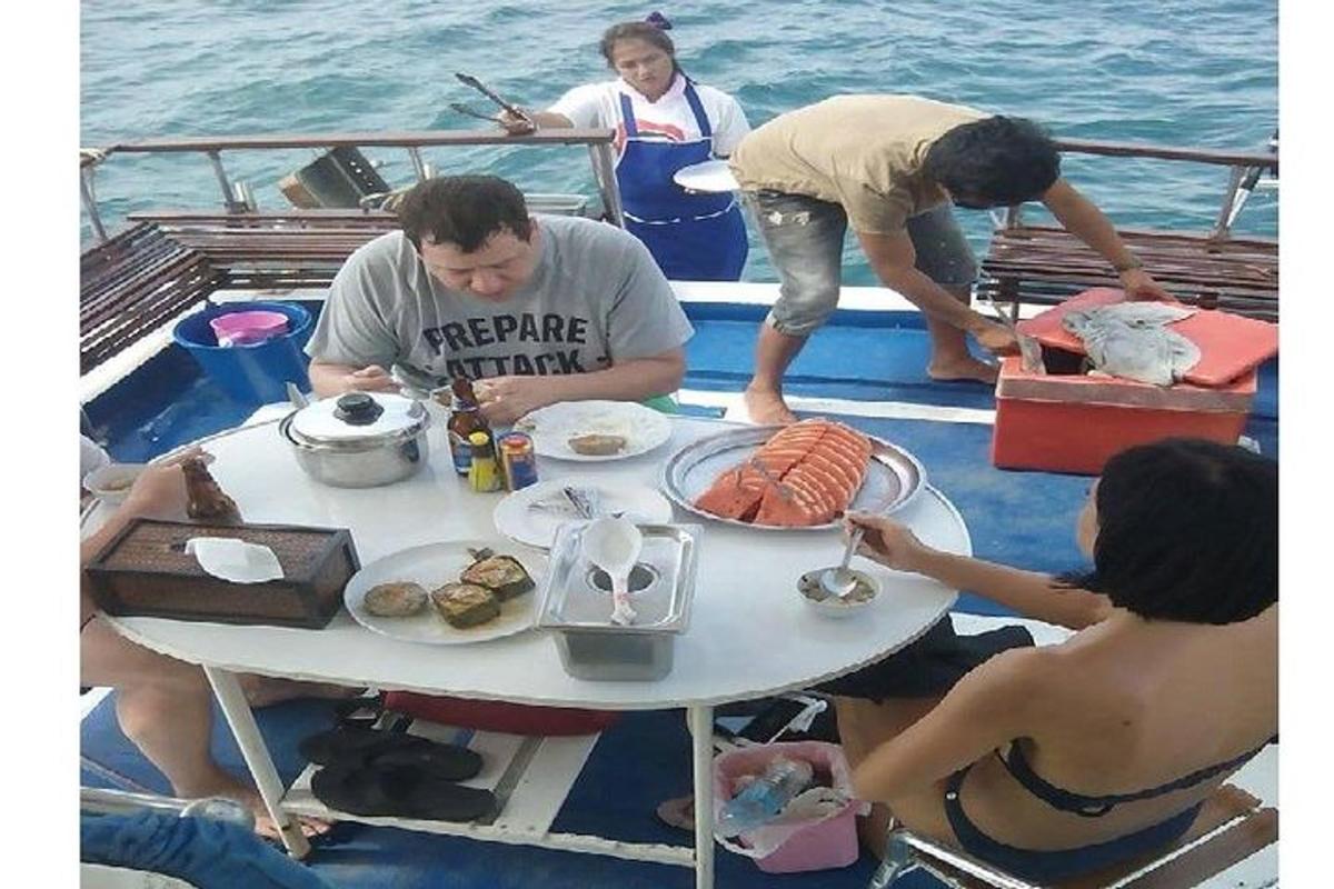 hópur fólks situr við borð á báti