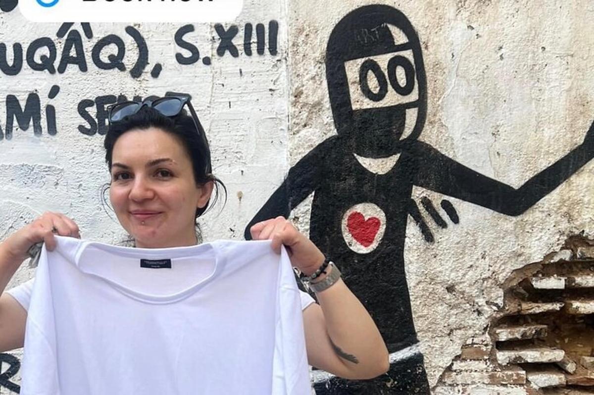 žena držící bílé tričko s namalovanou osobou na zdi