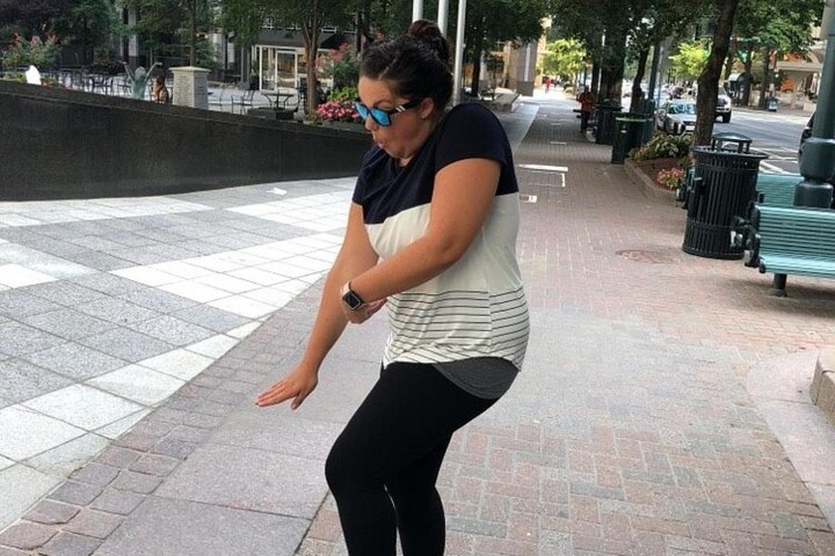 a woman riding a skateboard down a sidewalk