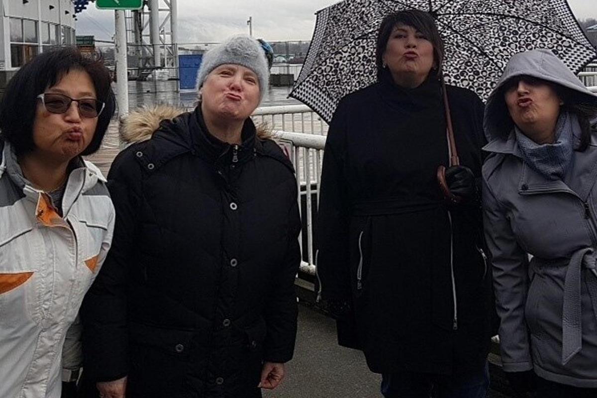 a group of women standing together in the rain with umbrellas