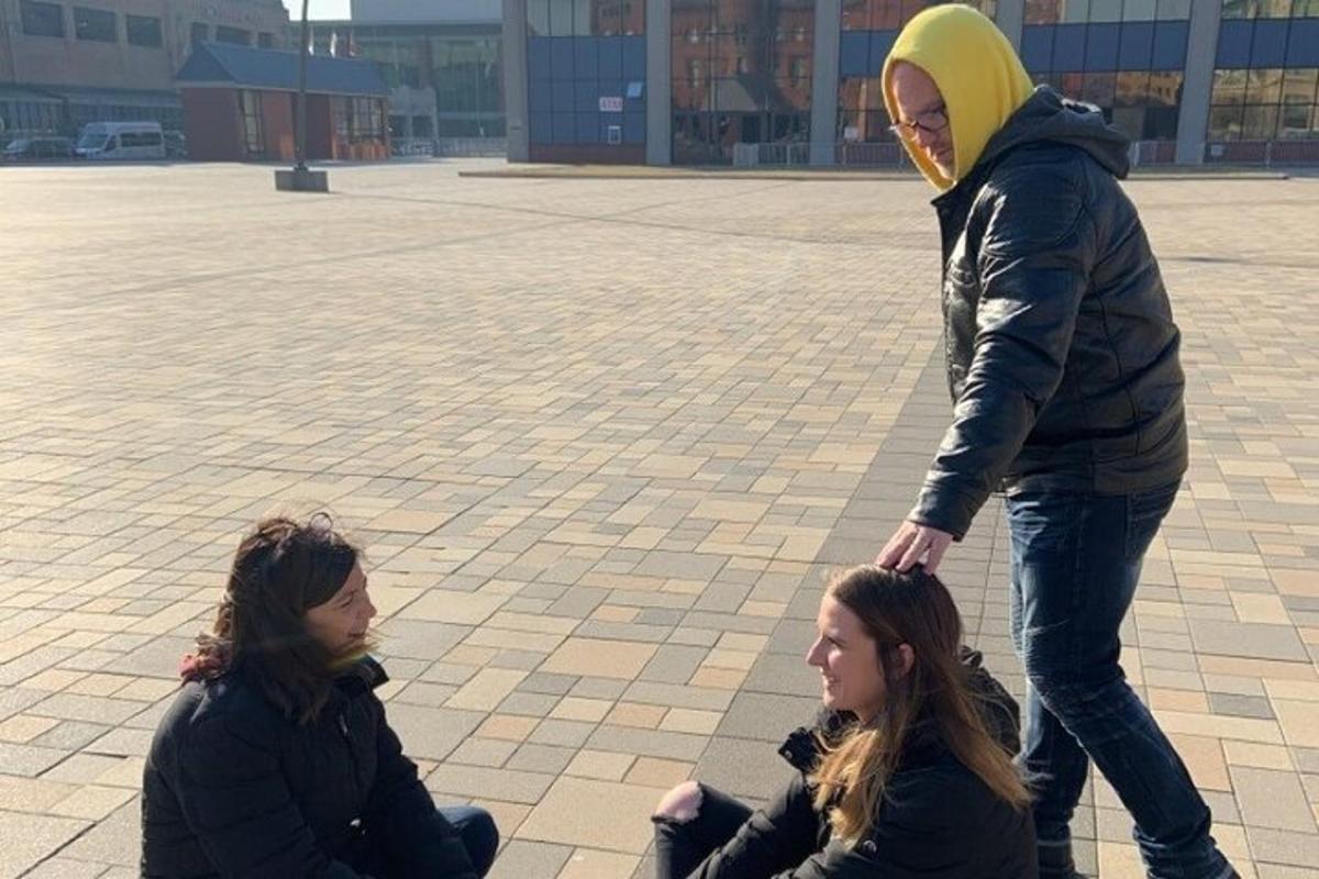 dvě dívky sedící na zemi a muž stojící