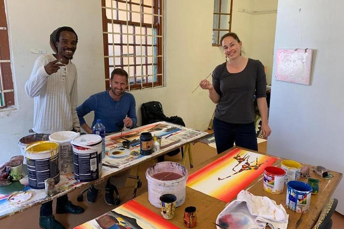 Un grupo de personas de pie alrededor de una mesa con pinturas.