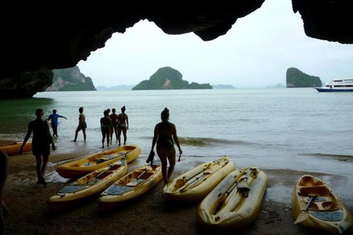 a group of people standing next to kayaks on the beach