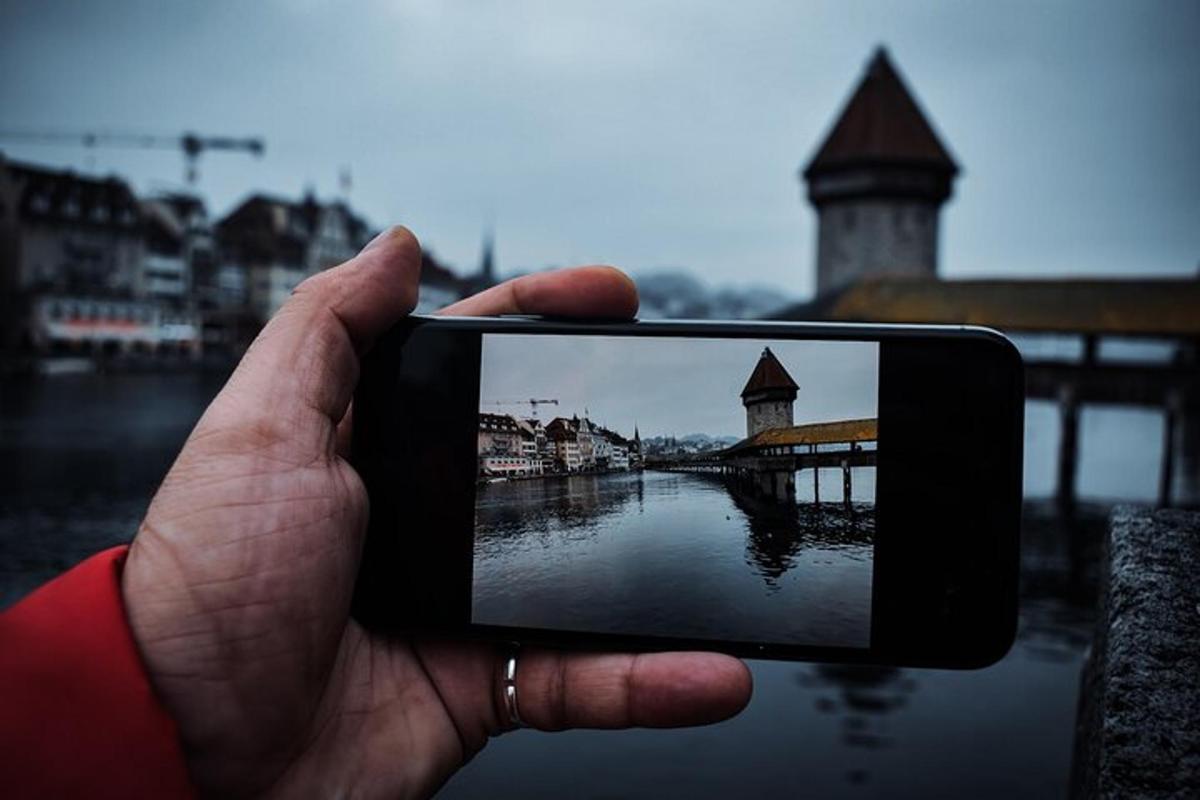 osoba držící mobilní telefon a fotící řeku