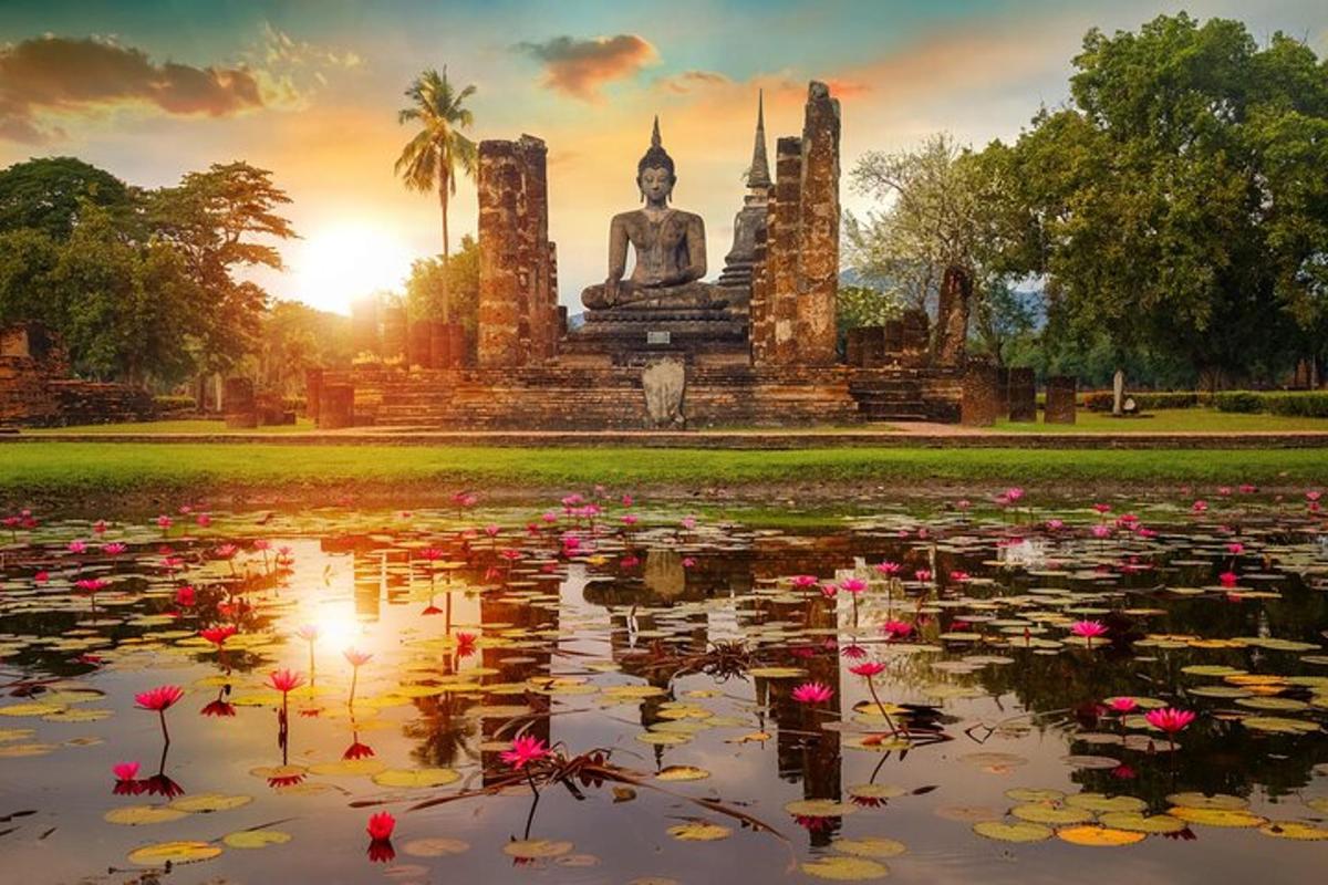 Una estatua de Buda en un estanque con flores delante.