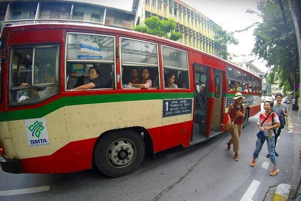 un autobus rosso che percorre una strada con persone che scendono