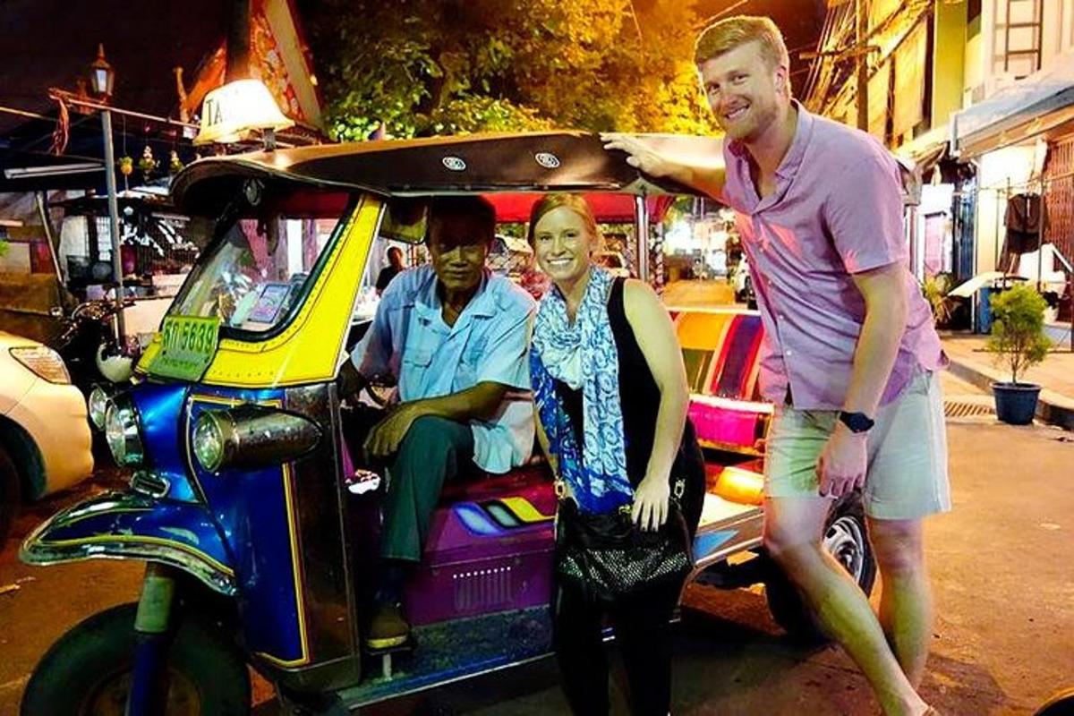 Dos hombres y una mujer de pie junto a un carrito de golf.