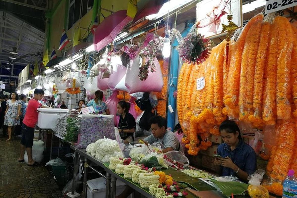 Un mercado con gente de pie alrededor de una exhibición de comida.
