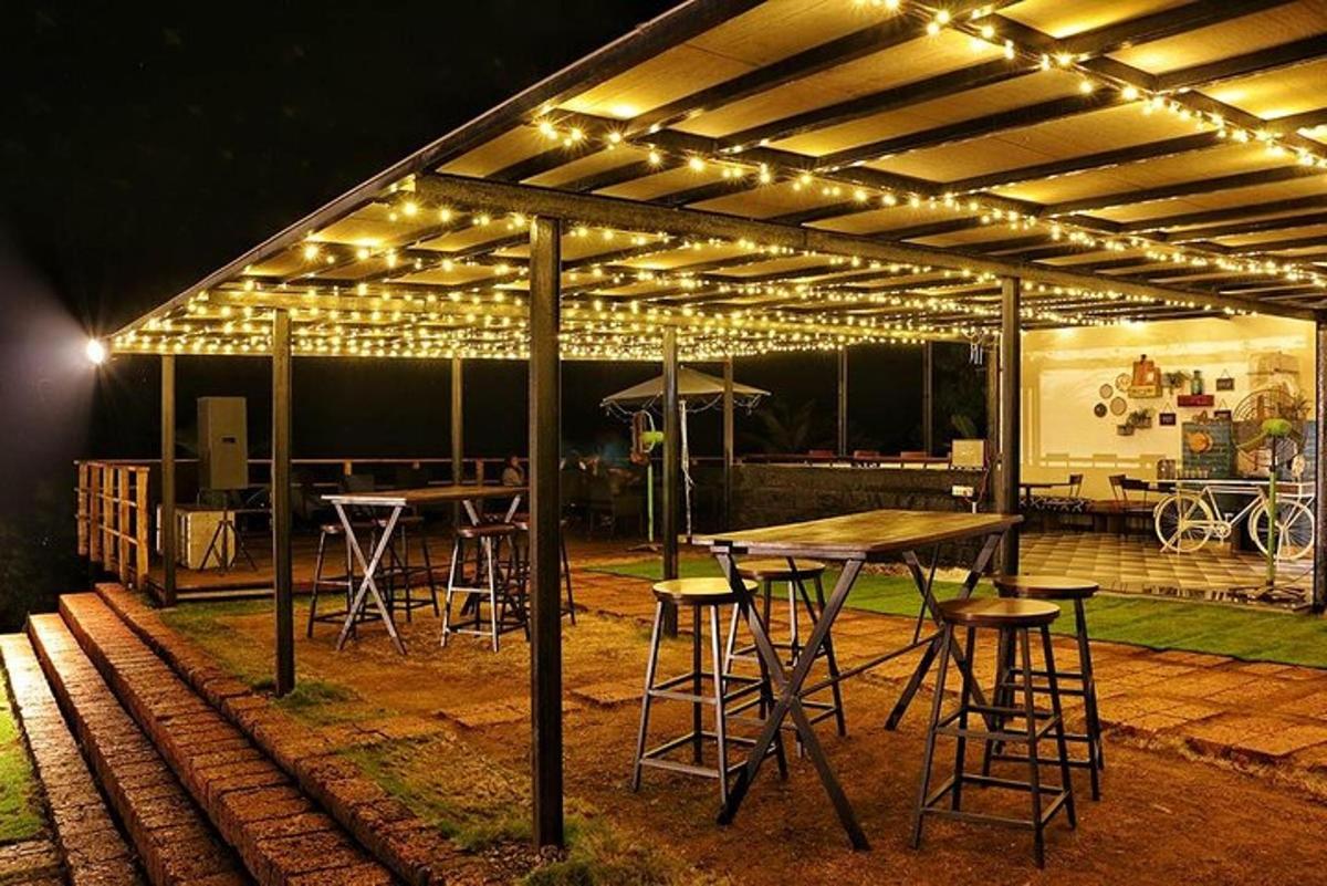 a patio with tables and chairs under a pavilion with lights