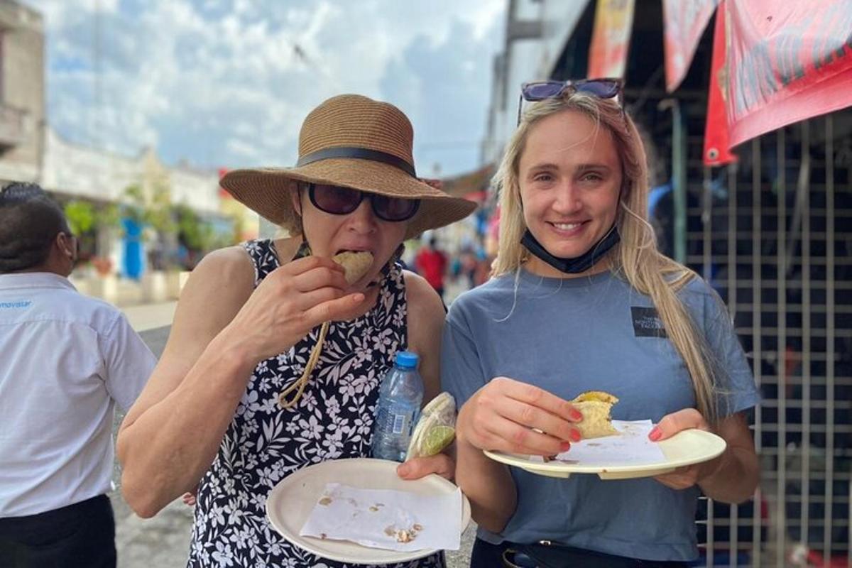 two women eating food on plates on a street