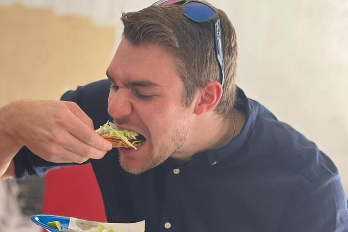 egy férfi napszemüveggel a fején, és szendvicset eszik