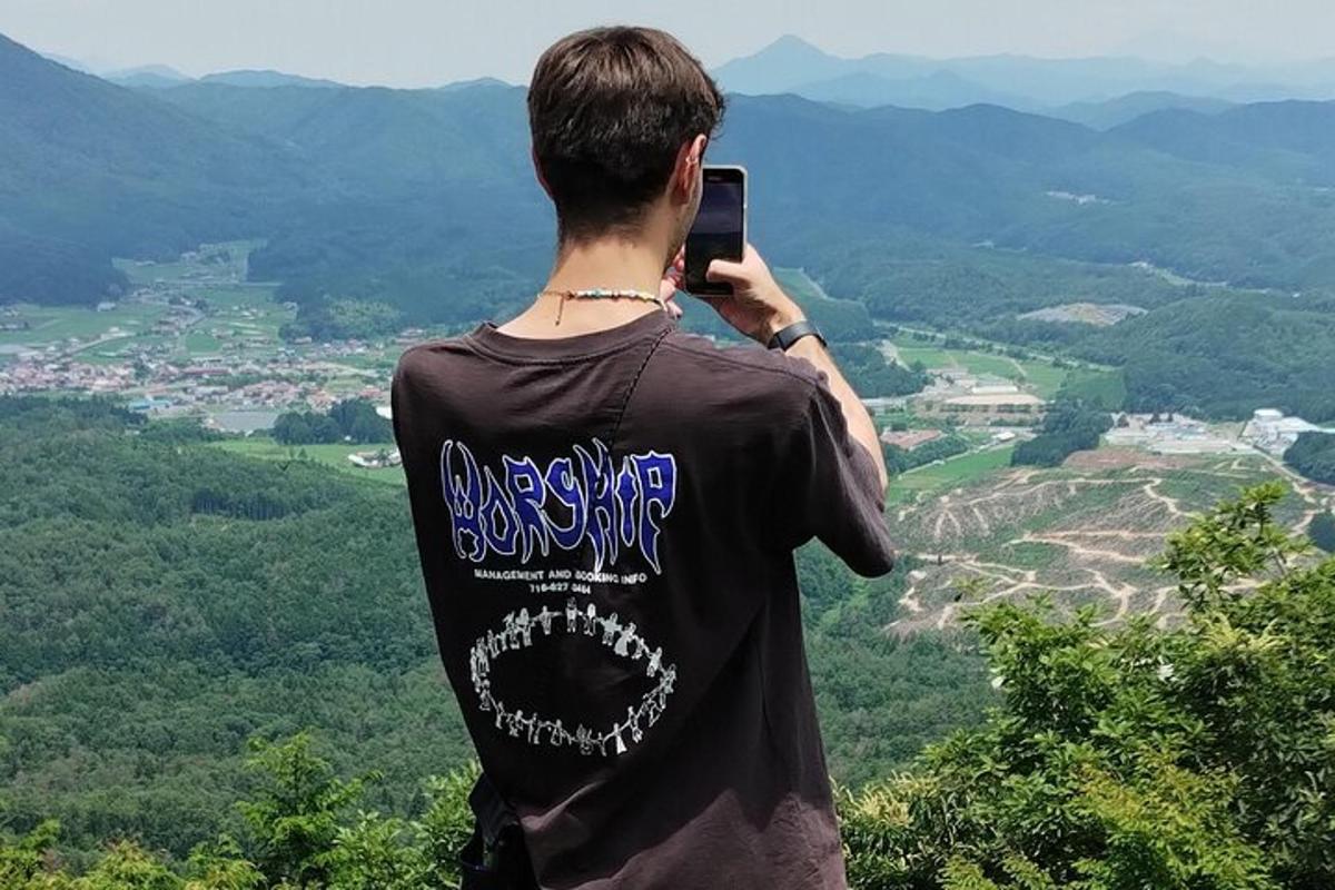 muž fotí údolí mobilním telefonem