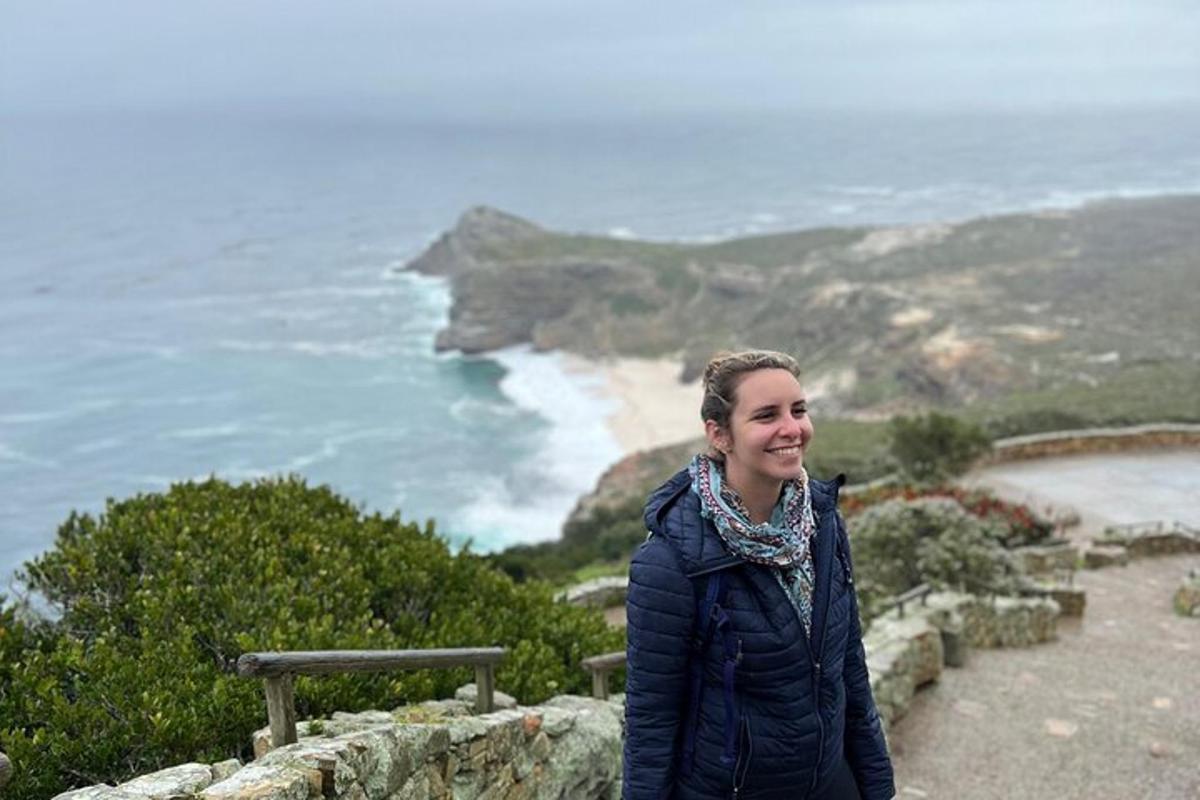 en kvinne som står på toppen av en klippe med utsikt over havet