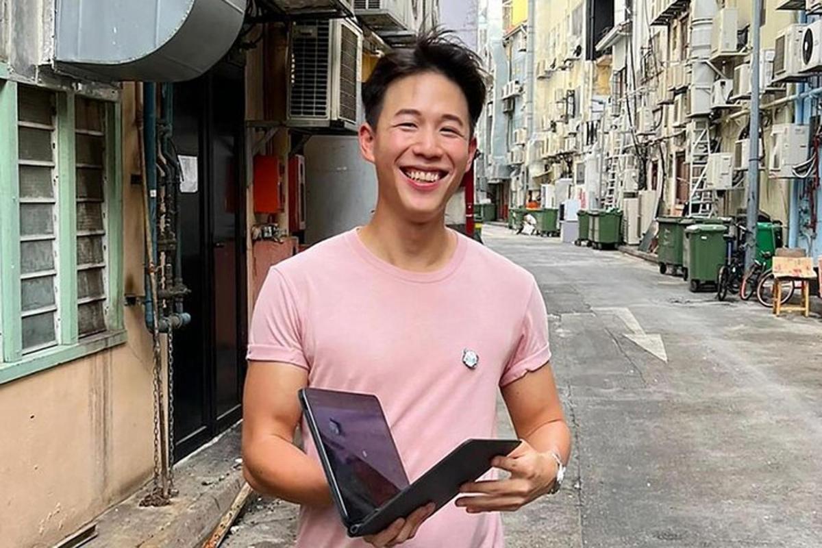 a man in a pink shirt holding a laptop