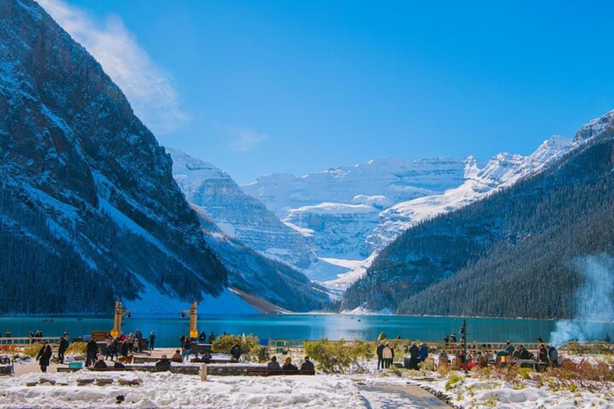 a group of people standing around a lake in the mountains