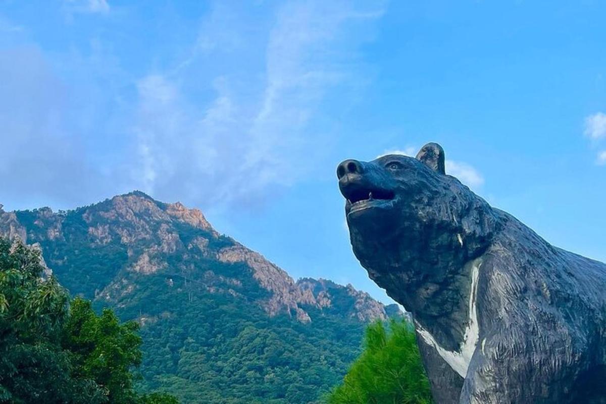 uma estátua de um urso em pé em frente a uma montanha