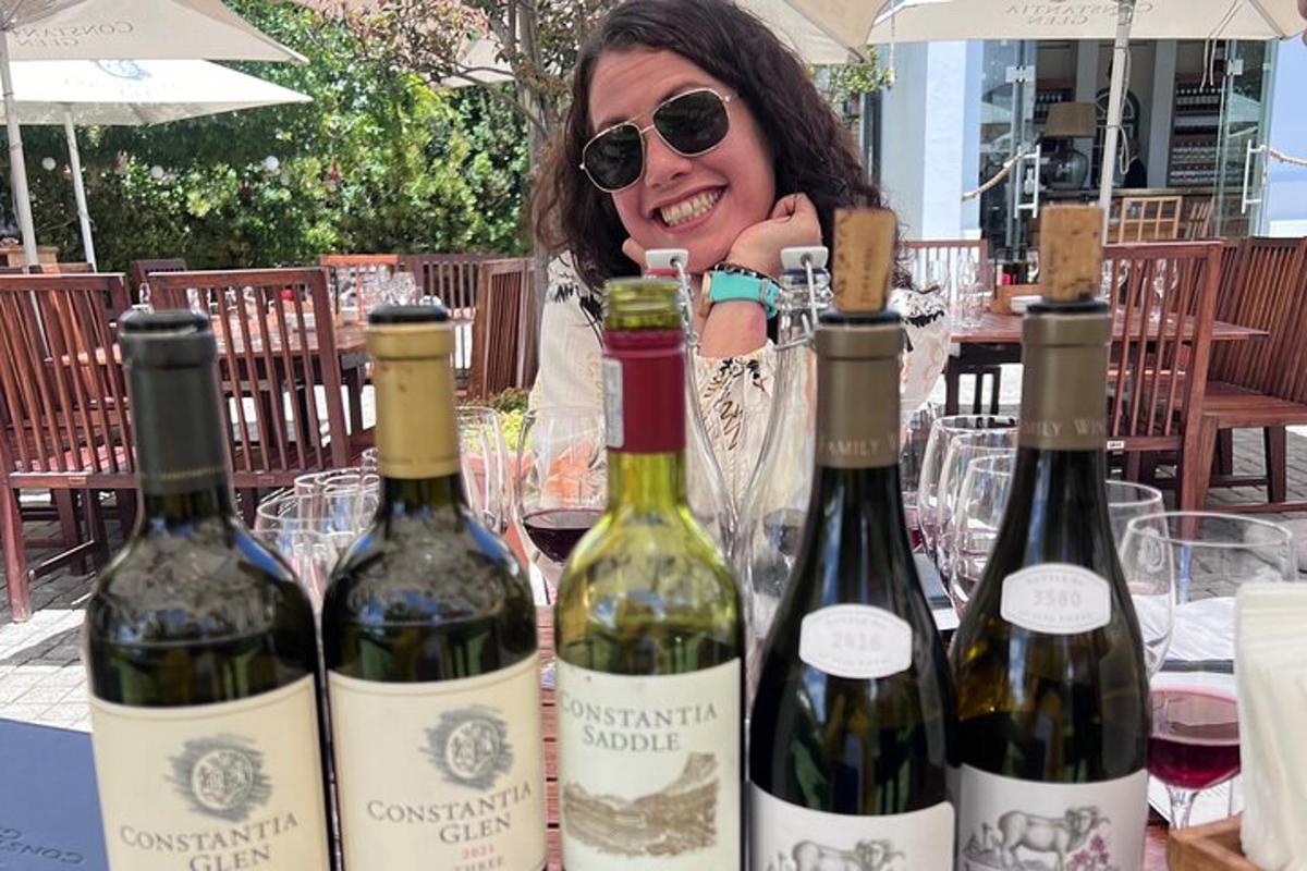 eine Frau sitzt mit vier Flaschen Wein an einem Tisch