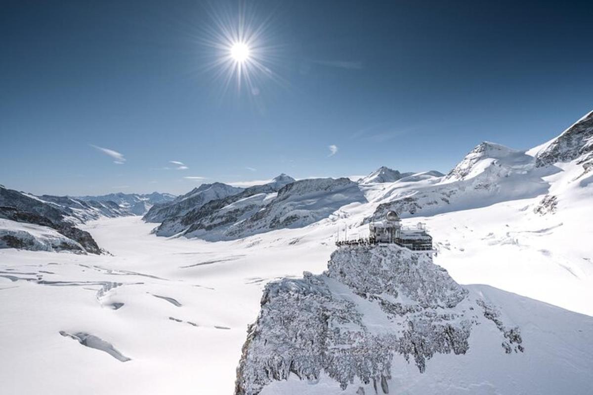 a snow covered mountain with the sun on top of it
