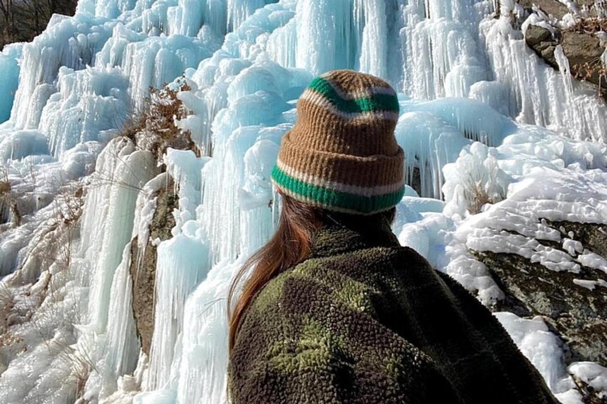 een vrouw kijkt naar een bevroren waterval