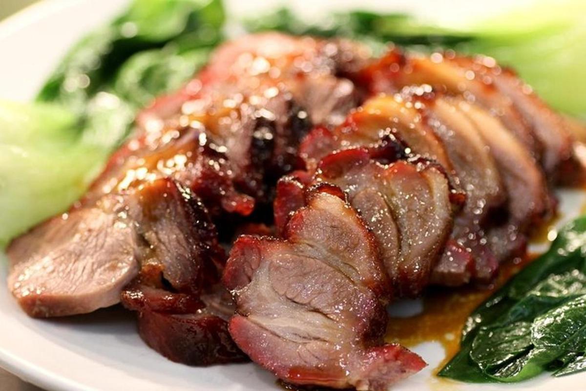 Un trozo de carne con salsa en un plato con verduras.