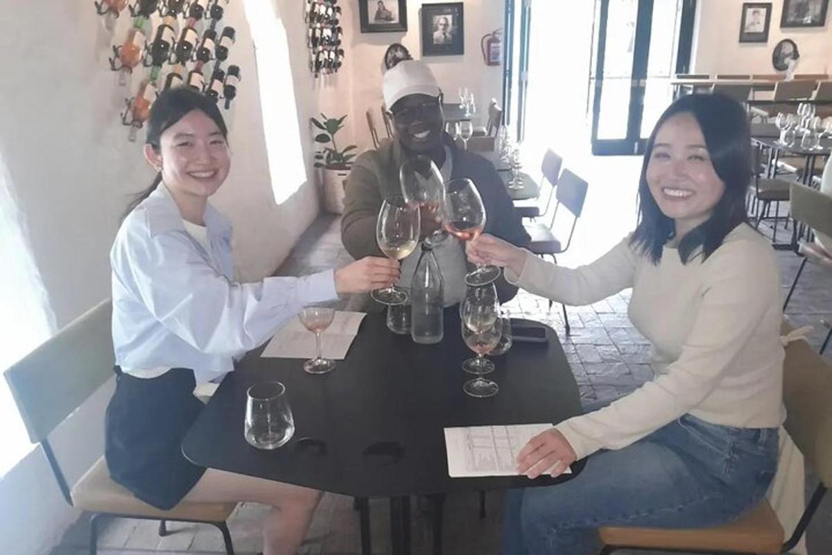 Dos mujeres y un hombre sentados en una mesa con copas de vino.