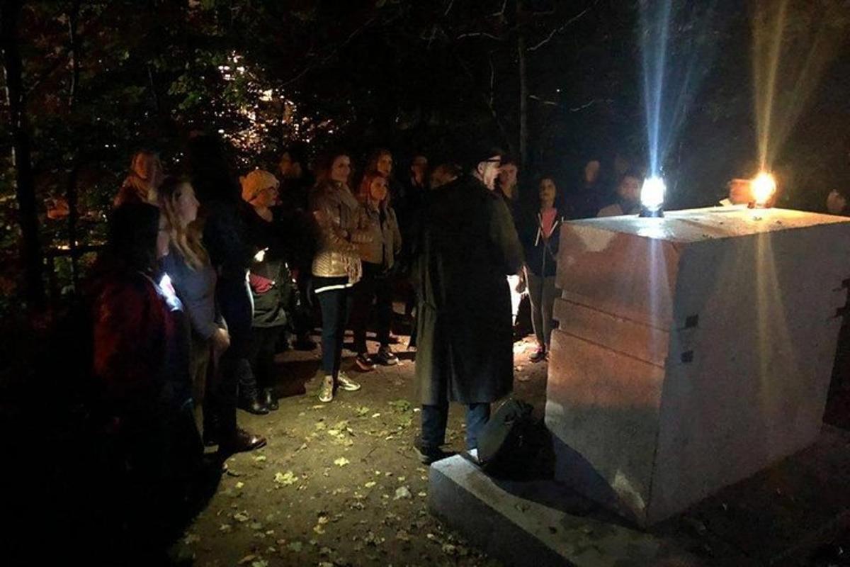 muž stojící před osvětleným objektem s davem