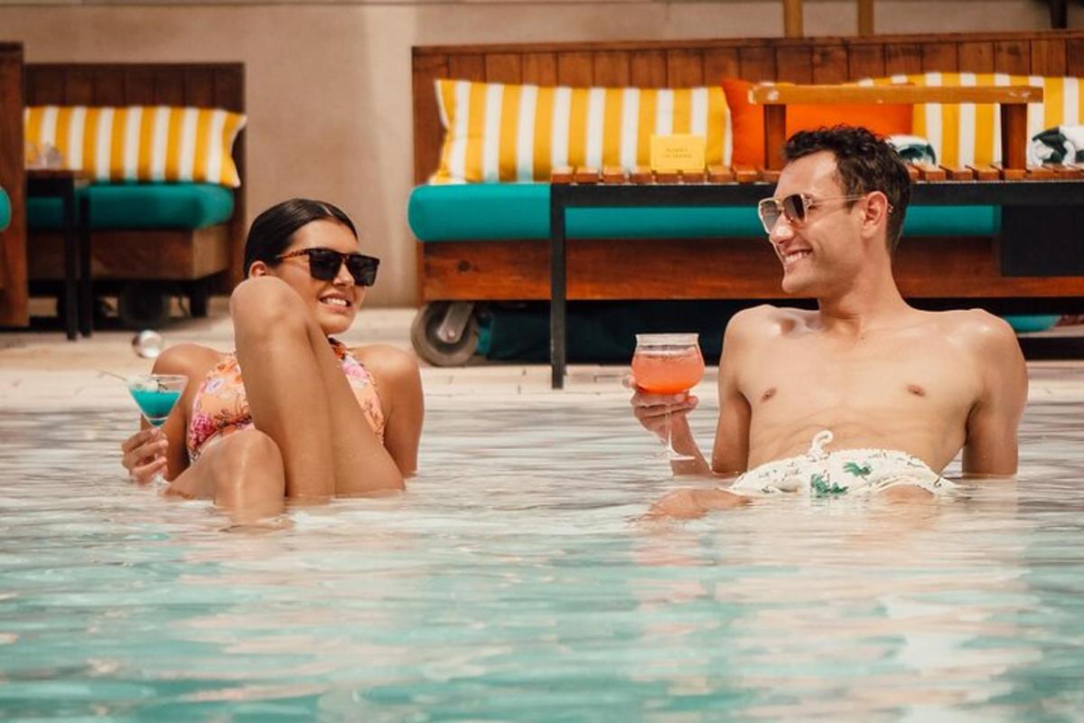 um homem e uma mulher em uma piscina com bebidas