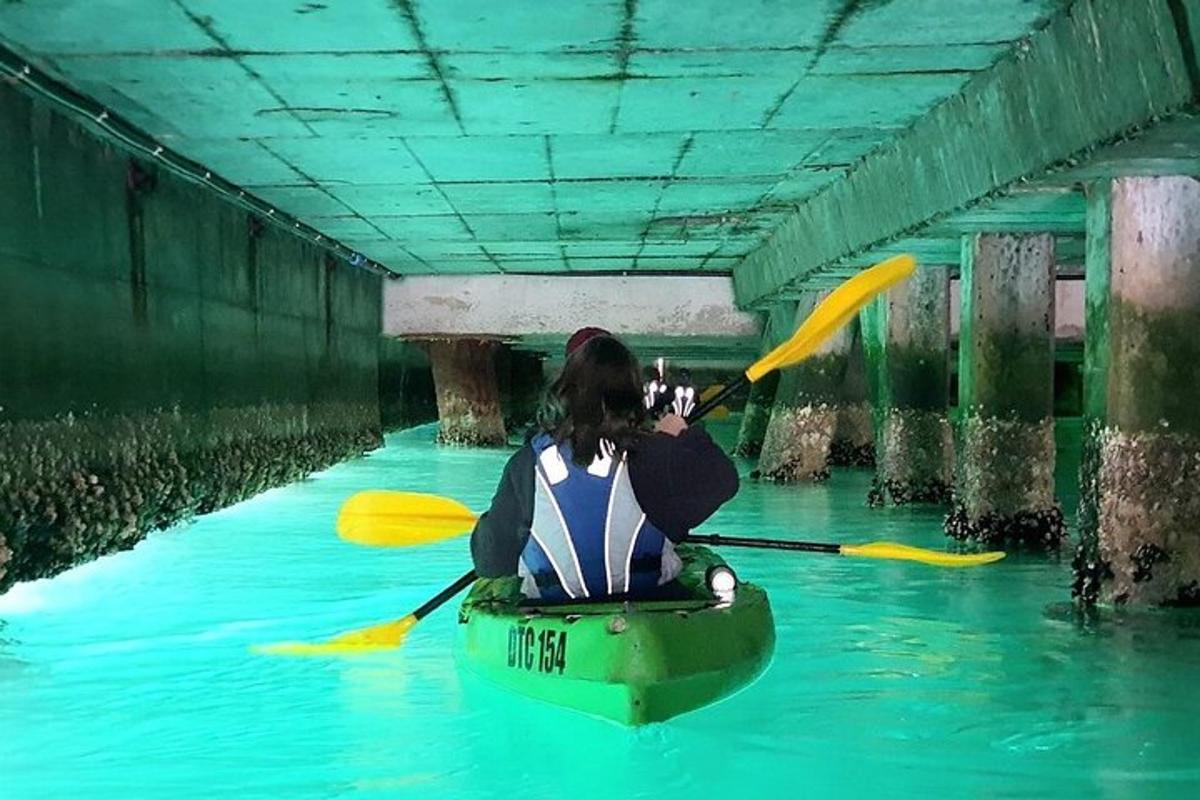 a person in a kayak in the water under a bridge