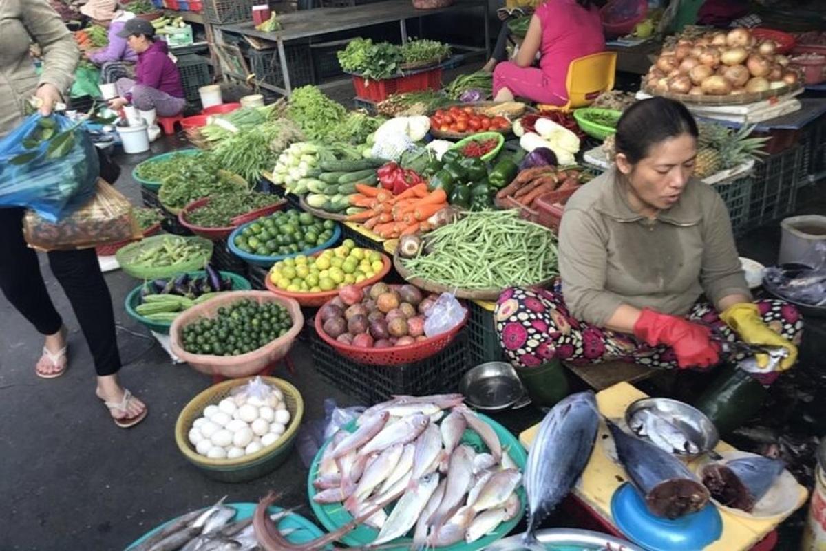 uma mulher sentada em frente a um mercado cheio de vegetais