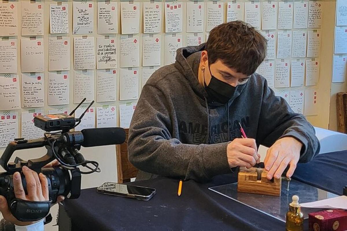 un uomo con una maschera che scrive su un pezzo di legno