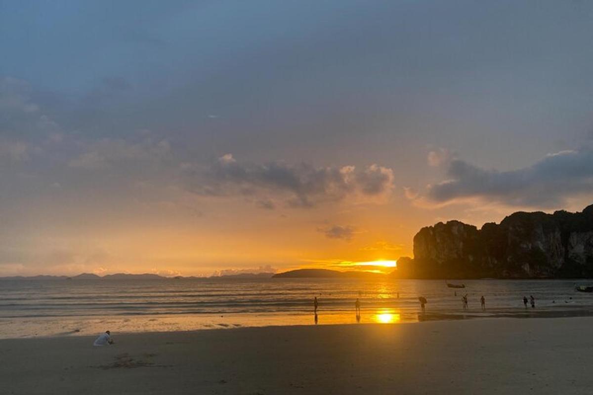 un tramonto su una spiaggia con persone in acqua