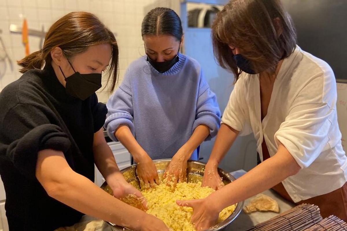 drei Frauen in einer Küche, die Essen in einer Pfanne zubereiten