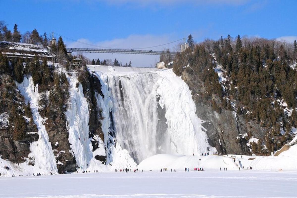 a group of people standing in the snow near a waterfall