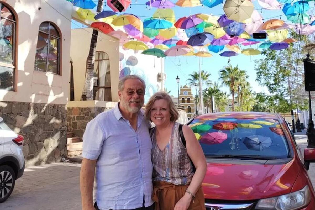 a man and woman standing in front of a car with umbrellas