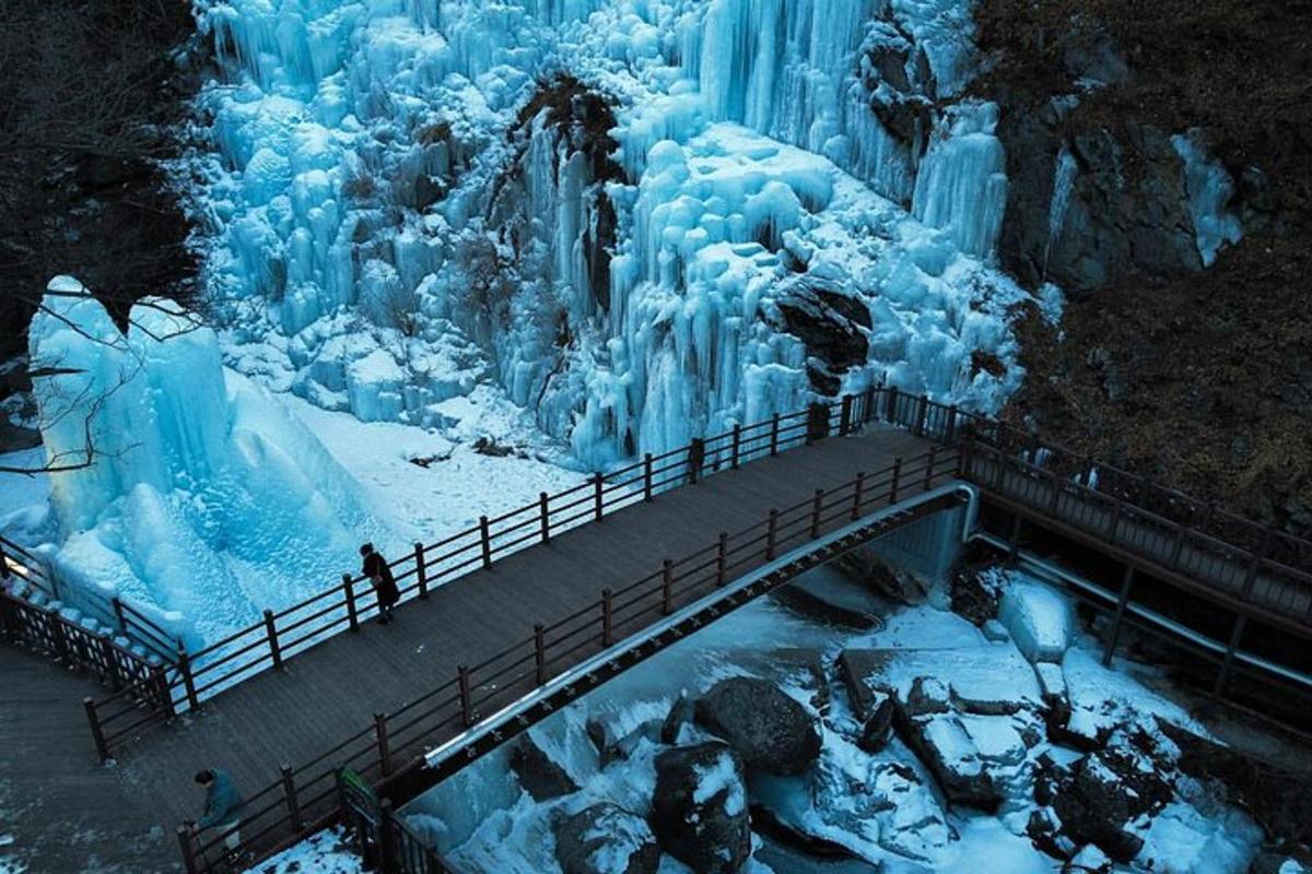 Un puente sobre una cascada congelada con gente parada en él.