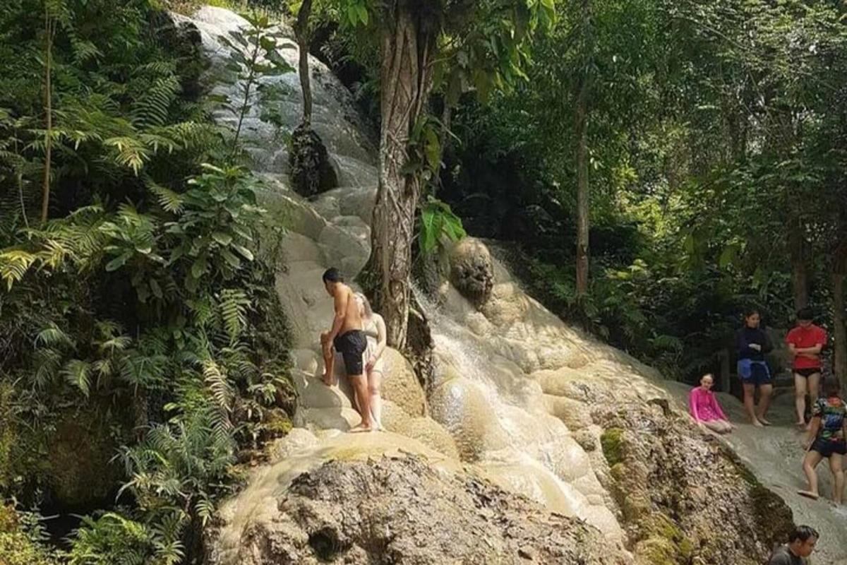 um homem descendo uma colina rochosa com uma cachoeira